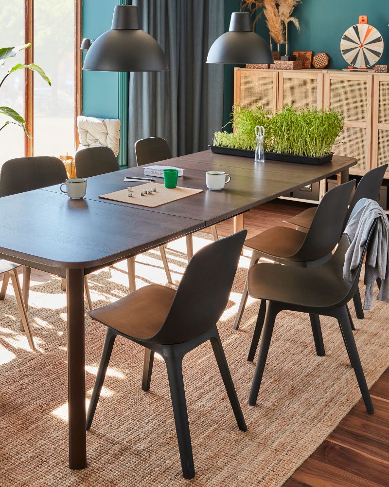 Modern dining area with STRANDTORP table, ODGER chairs, SKURUP lamps, LOHALS rug, STENFRÖ curtains and IVAR shelving.