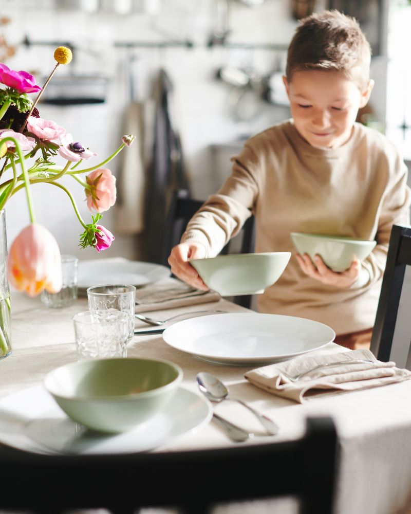 Elegant dining room with FÄRGKLAR bowls, OFTAST plates, DRAGON spoons, FRÖJDA glasses and STEFAN chairs.