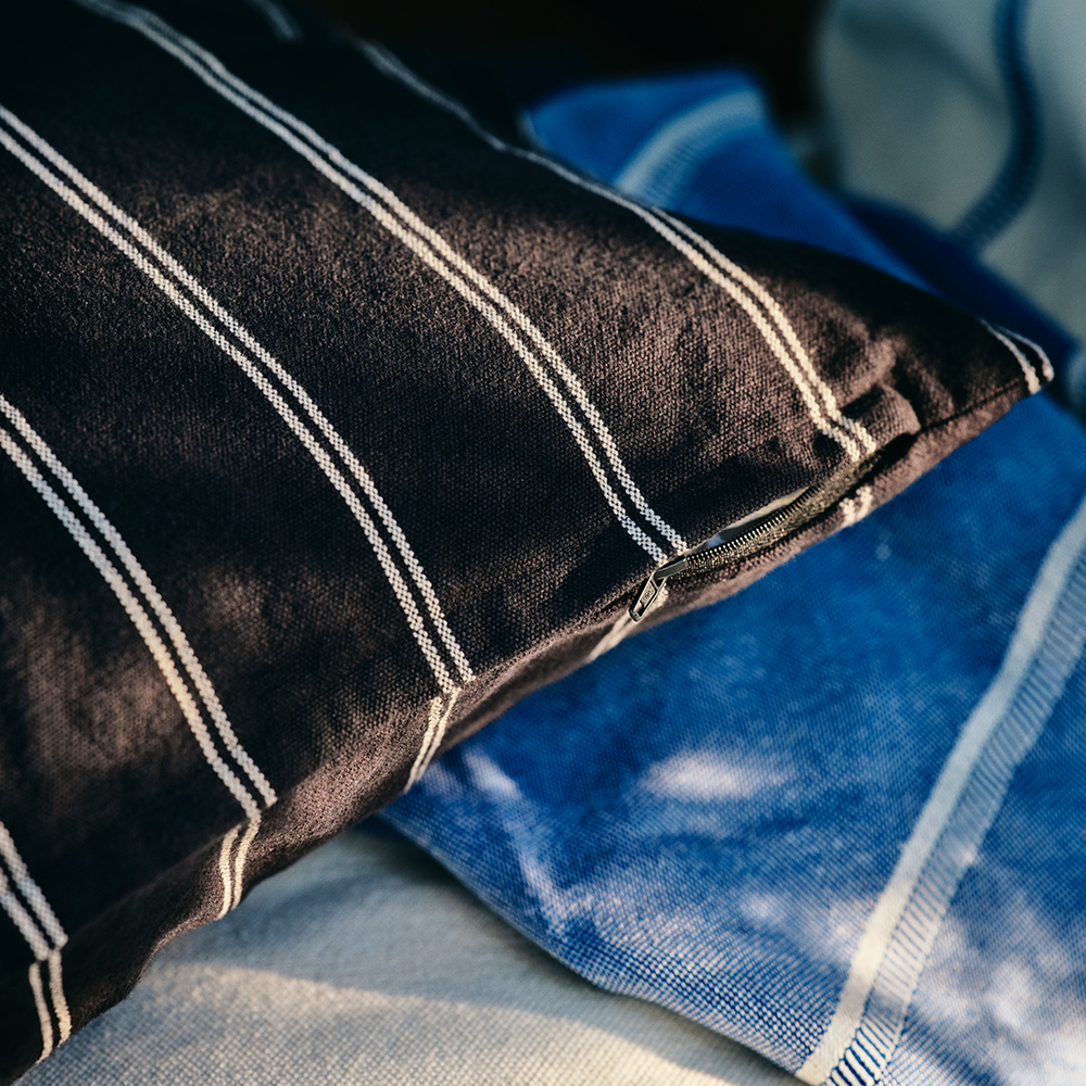 A SOLUPPGÅNG cushion cover with black and white stripes is on top of a SOLUPPGÅNG throw.