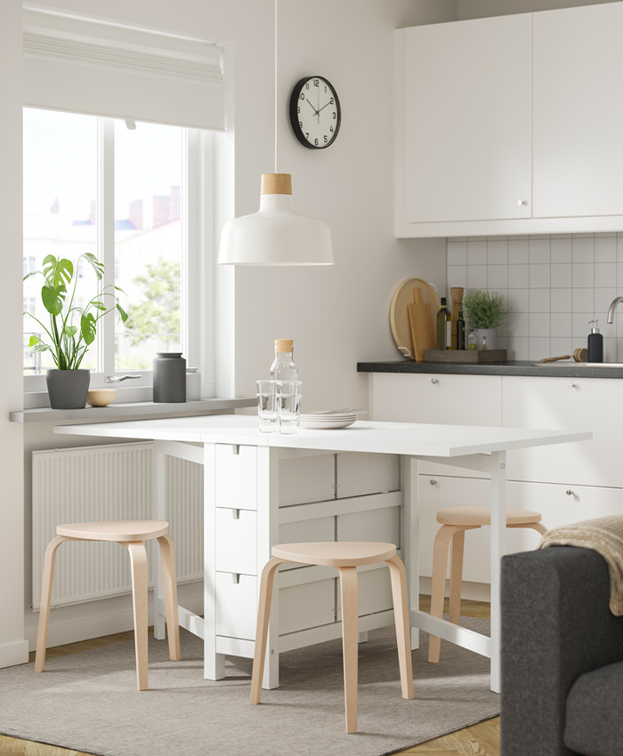 Bright kitchen with white folding table and wooden stools.