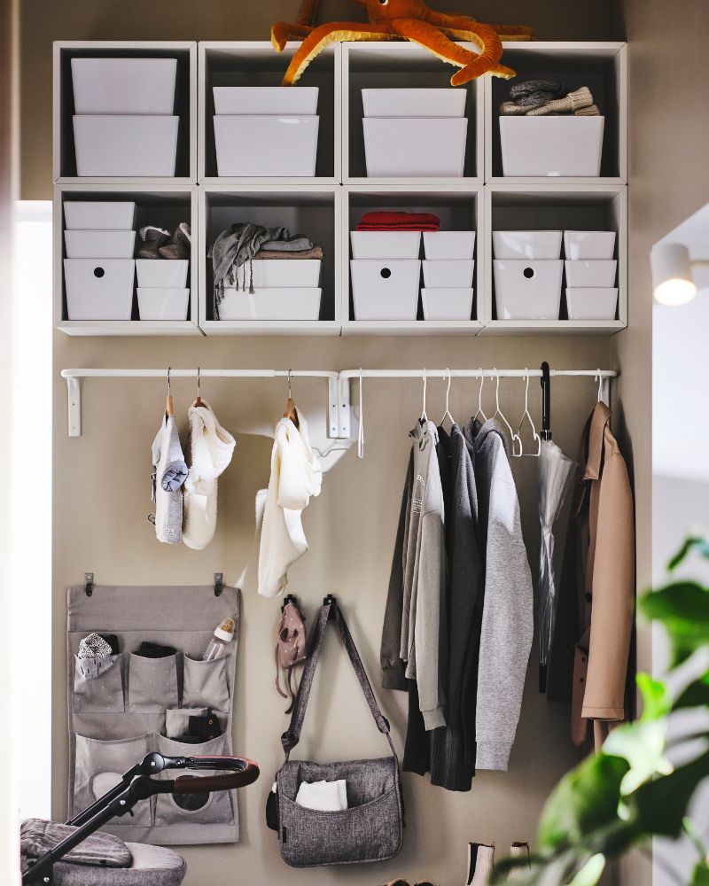 Wall-mounted EKET shelves with KUGGIS boxes and LEN organizers, paired with MULIG clothing rail and assorted hooks for easy storage.