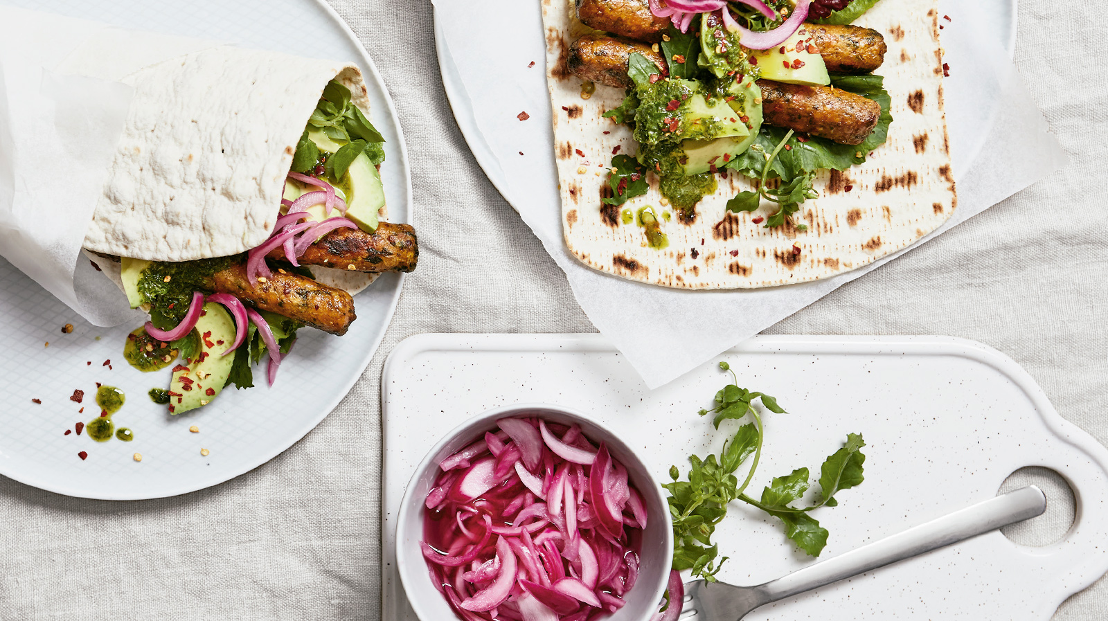 Vegetable hot dogs with avocado, herb salsa, pickled red onion and chili flakes