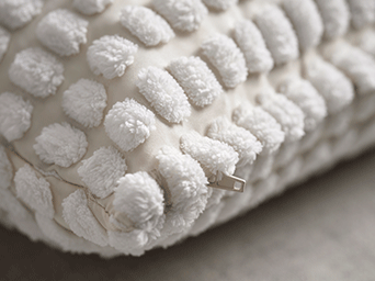 Close-up of a white textured cushion cover with soft tufts and a visible side zipper.