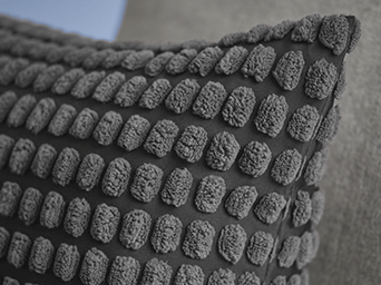 Close-up of a dark grey cushion cover featuring a dense, tufted popcorn texture.