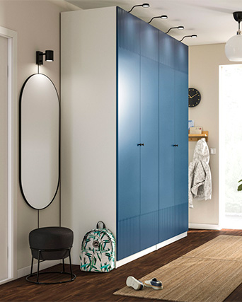 Modern blue wardrobe in an entryway with mirror, bench, and decorative accessories.