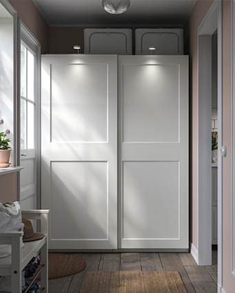 White wardrobe with smooth doors in a bright hallway with natural light.