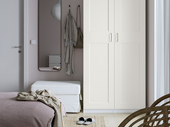 White wardrobe in a bedroom with classic doors next to a bench and mirror.