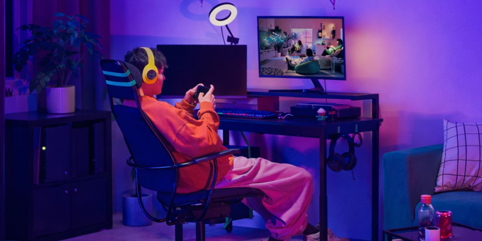 A neon‑lit gaming room with the UTVISNING desk and LÖPARBANA chair, enhanced by the LÅNESPELARE ring light for a vibrant setup.