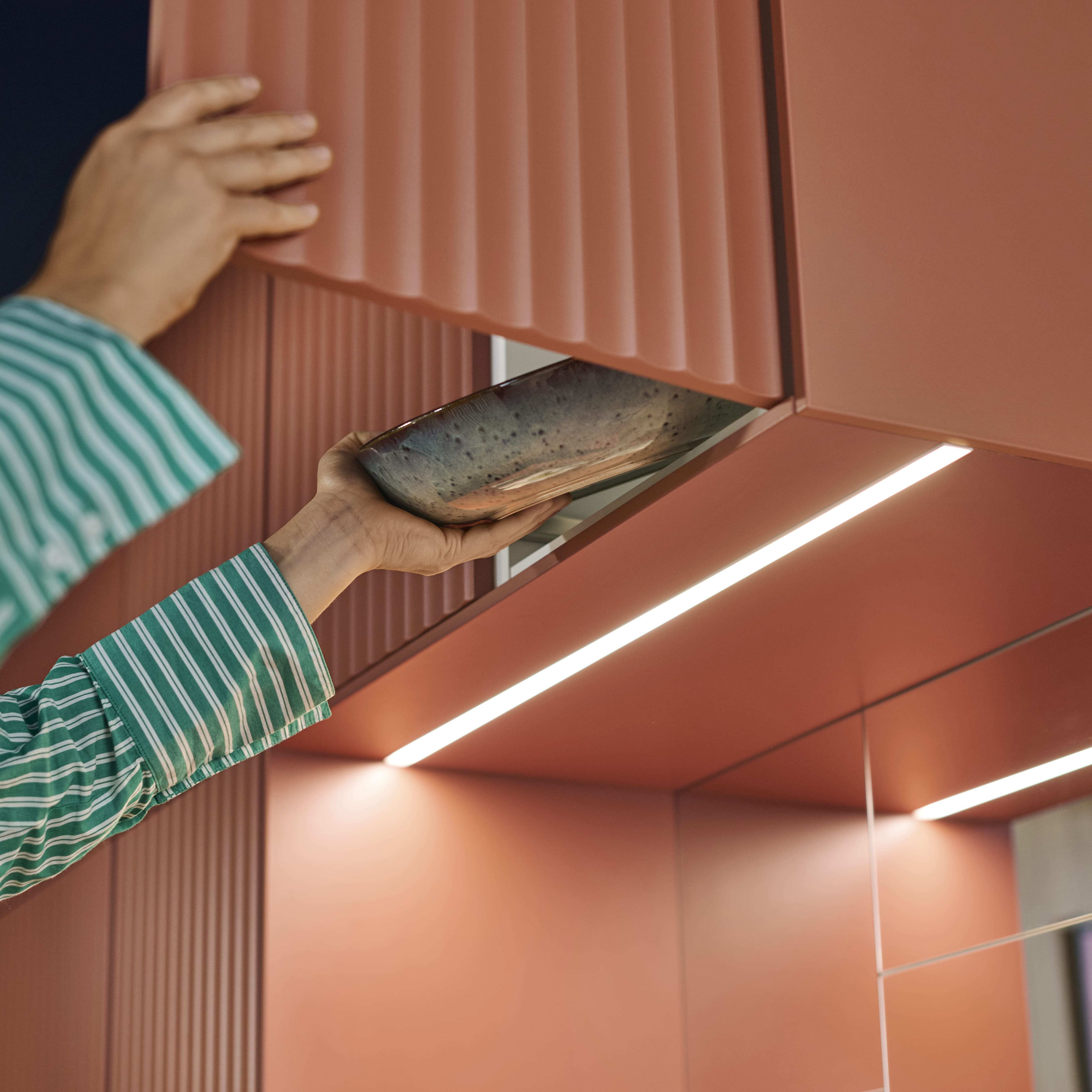 Reddish-brown kitchen countertop featuring an induction hob with a steaming pot and fresh vegetables near a window with plants.