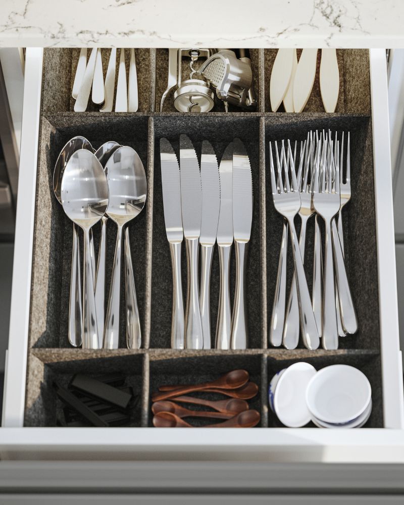Organized kitchen drawer with IKEA UPPDATERA utensil tray, DRAGON cutlery and IDEALISK corkscrew neatly arranged.