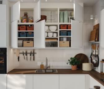 Open white kitchen cabinets with boxes, dishes, and utensils organized above the countertop.