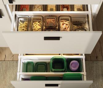 Open kitchen drawers with storage containers organizing pasta, grains, and plastic food containers.