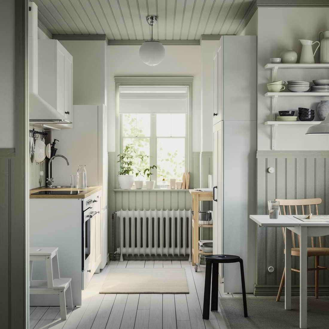 A narrow, rustic-style kitchen with light green paneled walls, white cabinets, and a small dining table.