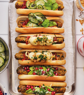 Bandeja con hot dogs variados con vegetales y salsas decoradas