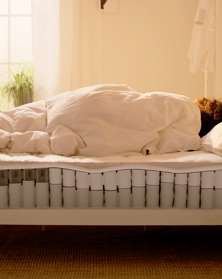 Person lying on a mattress with visible internal spring layers, demonstrating support and comfort.
