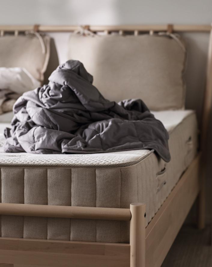 Bedroom scene with a mattress and crumpled blanket on top, highlighting a cozy sleeping space.