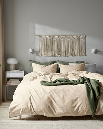 Primer plano de la esquina de un colchón beige texturizado con un asa de tela, descansando sobre una base de cama blanca de estilo minimalista.