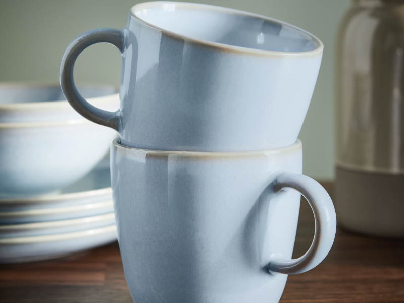 Two ceramic mugs stacked on a wooden table.