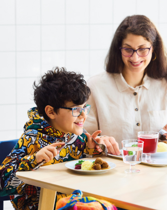 Persona adulta y niño comiendo juntos en una mesa.
