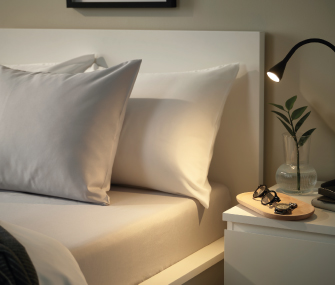 White pillows on a bed with a lit nightstand.
