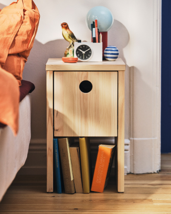 Mesita de noche de madera con libros y reloj.