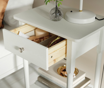 Mesa de noche blanca con cajón abierto y lámpara.