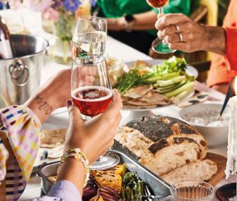 Personas brindando alrededor de una mesa con comida compartida.