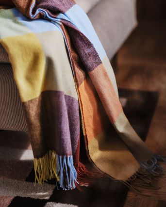 Sala acogedora con sofá SÖDERHAMN, cobija FLIKHAGTORN y alfombra MARKBLÅMME en tonos cálidos otoñales.