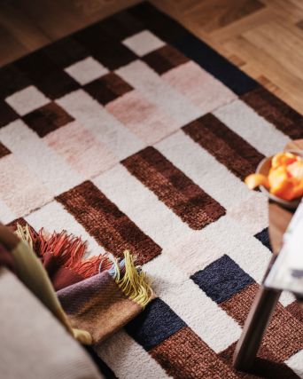 Sala moderna con alfombra MARKBLÅMME y cobija FLIKHAGTORN, destacando patrones geométricos llamativos.