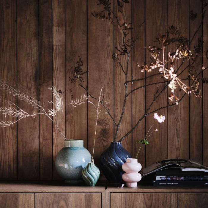 Estante decorativo con florero GLANSGRAN, floreros KORNSPARV y florero PÄRLHÄGG en un ambiente cálido.
