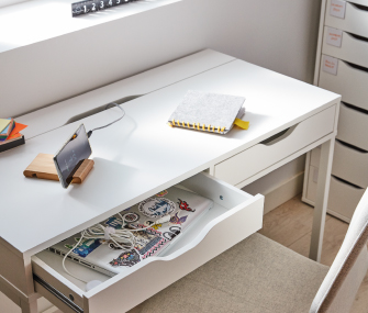White desk with an open drawer and notebook.