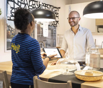Asesor de IKEA muestra una tableta a un cliente sonriente en la tienda.