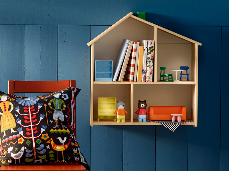 House-shaped wooden kids shelf with books and toys mounted on a blue wall.