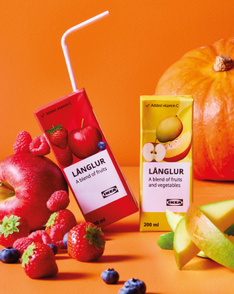 Bebidas de frutas y vegetales junto a frutas frescas sobre fondo naranja.
