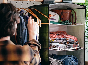 Person organizing clothes on a rack with a hanging fabric storage organizer.