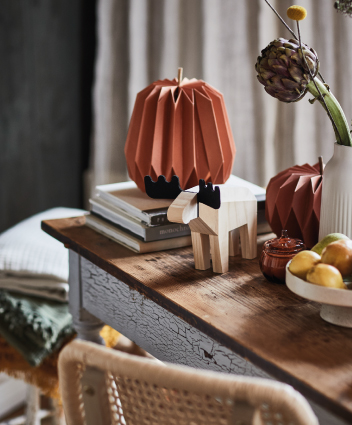 Decoración otoñal con figuras de papel, libros y accesorios sobre una consola de madera.