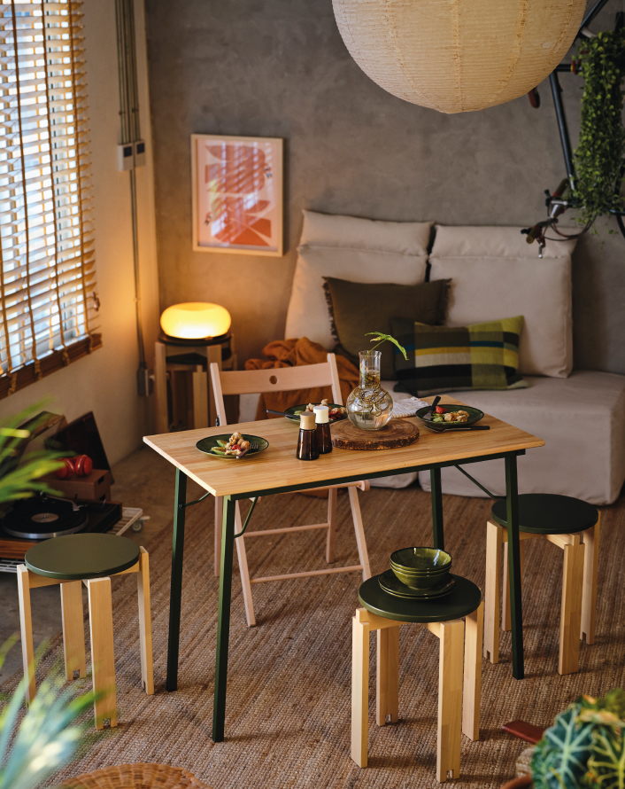 Small dining area with a wooden table, stools, and a sofa in a cozy living space.