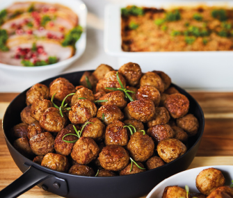 Sartén llena de albóndigas suecas servidas sobre una mesa con varios platos.
