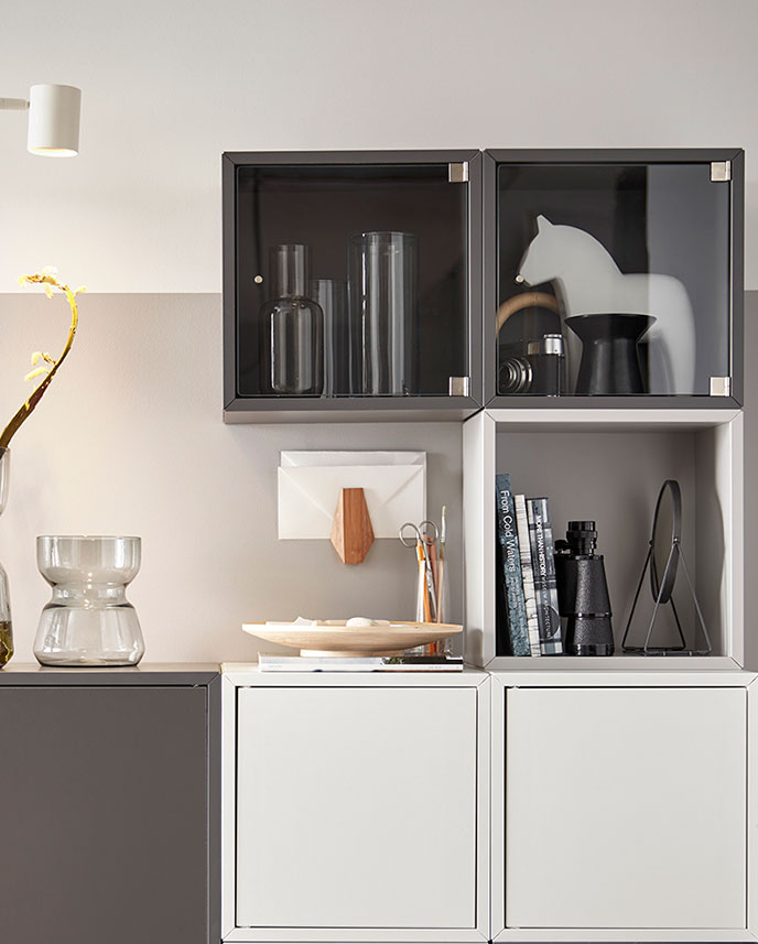 A living room with a dark grey EKET cabinet featuring two doors and a shelf, displaying decorative items.
